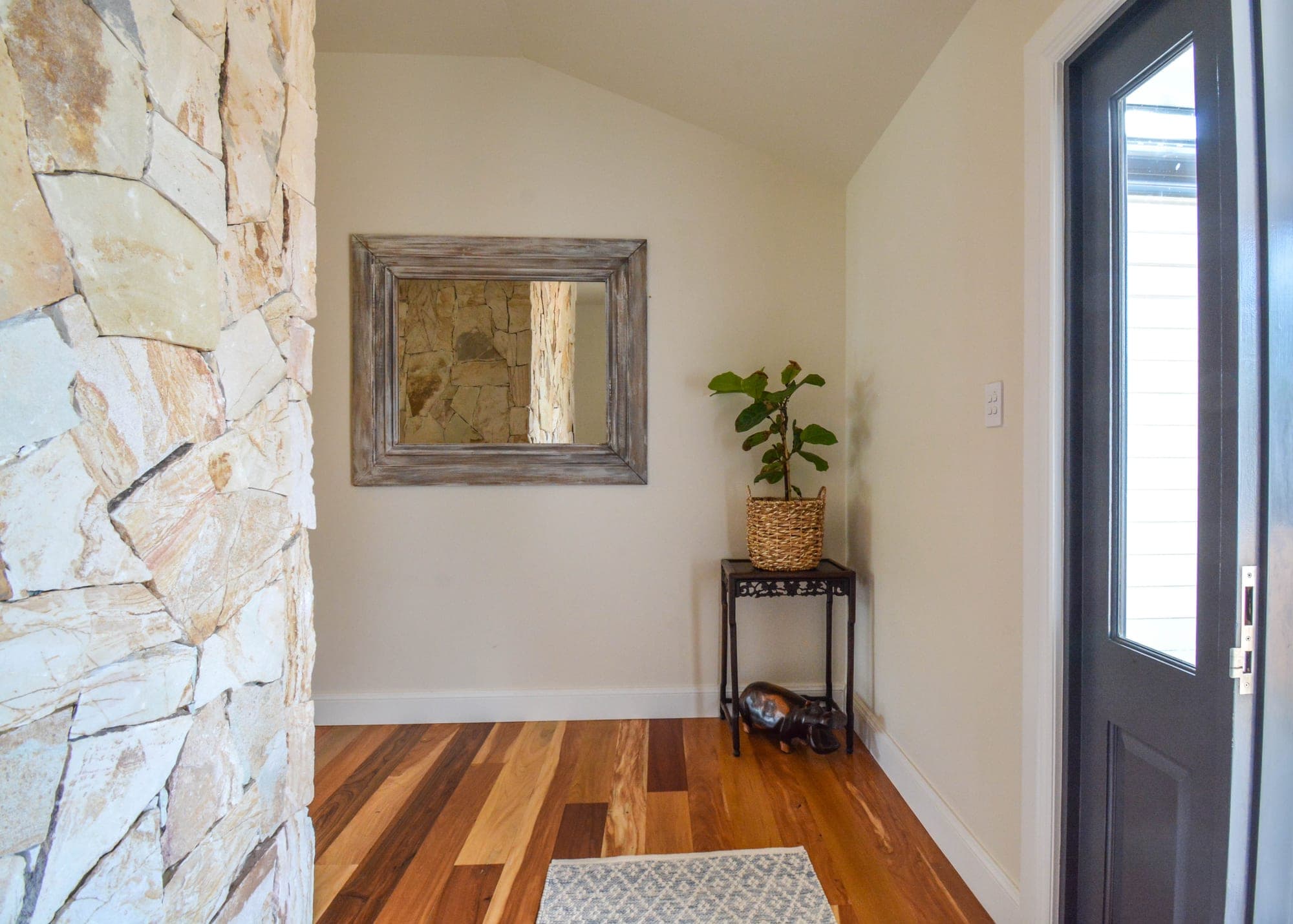 Entry foyer with stone-clad wall, timber door and polished concrete floor