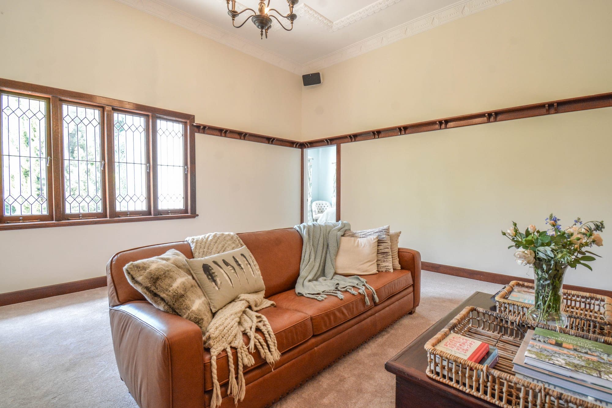 Living room with stone feature wall fireplace, leather sofa and timber floorboards