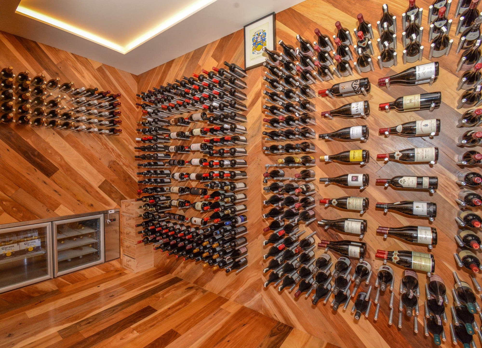 Herringbone brick wine cellar with floor-to-ceiling timber wine racks and warm pendant lighting