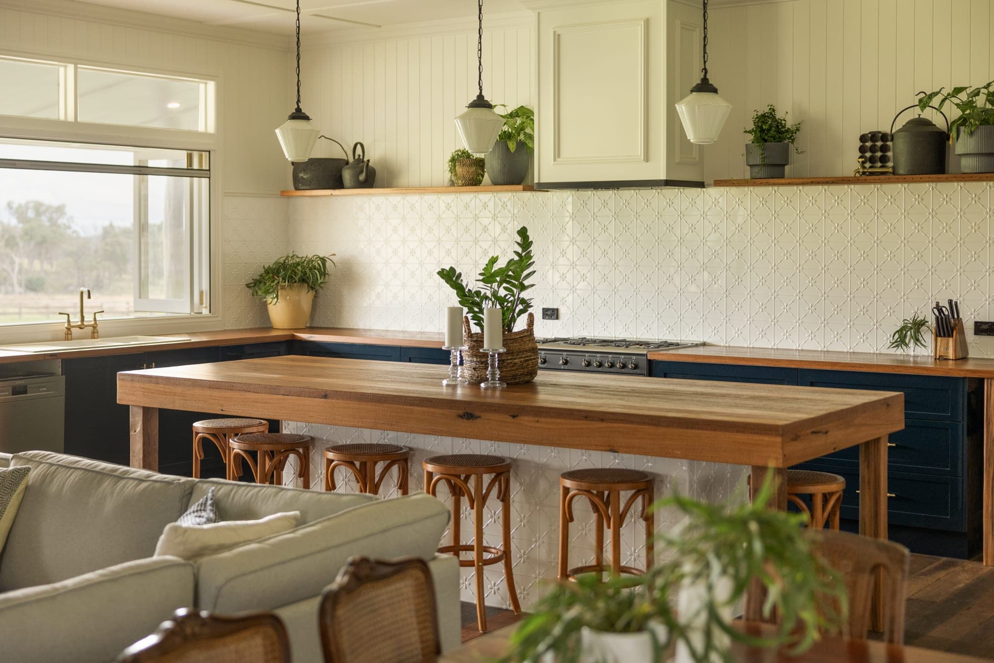 Kitchen with navy shaker cabinets, solid timber island bench, pressed-tin splashback and pendant lights