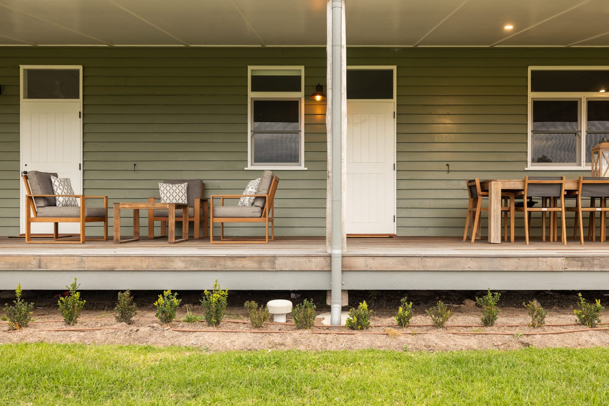 Front verandah of Mountain Station with sage green weatherboard cladding, timber deck and outdoor furniture